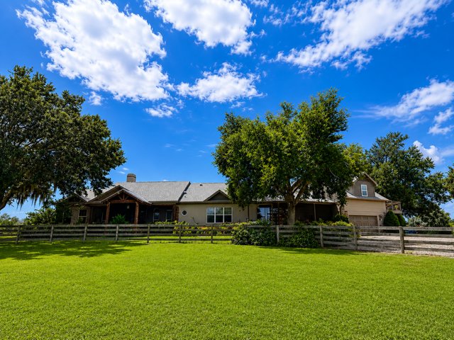 Main residence and oversized garage behind board fencing on a bright Florida day