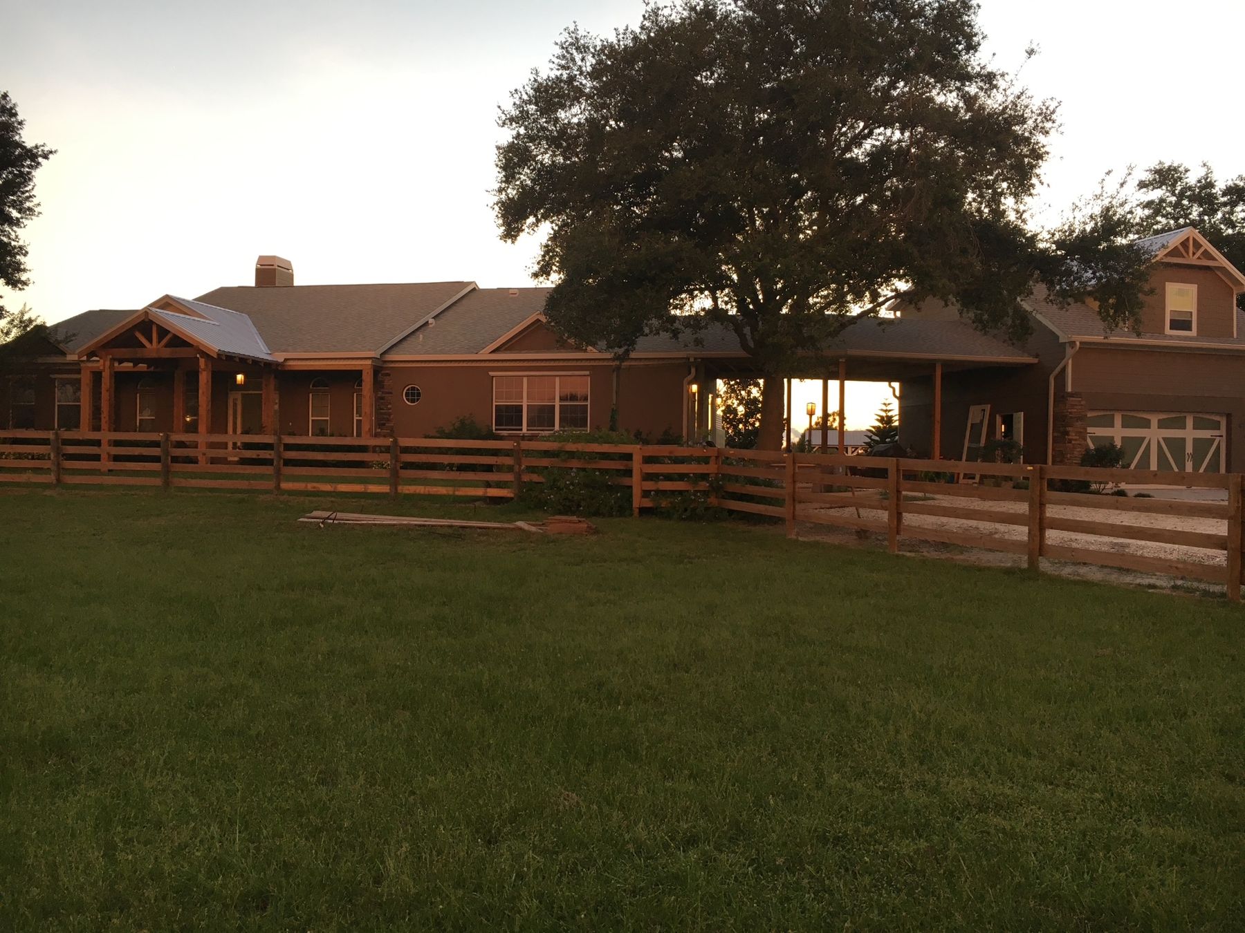 Main residence at sunset with board-fenced pasture